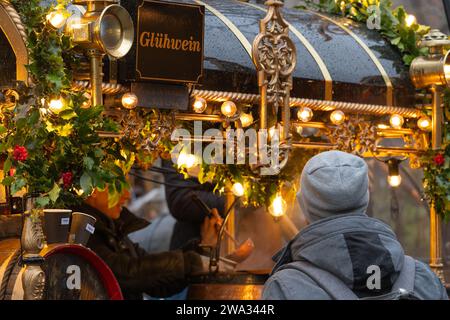 Eine Frau, die traditionellen Glühwein (Glühwein) in eine Tasse für einen Kunden auf dem Winchester Cathedral Christmas Market in Hampshire, Großbritannien, ausschöpft Stockfoto