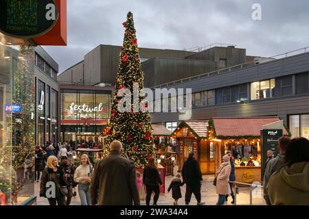 Weihnachtseinkäufer, Marktstände und Weihnachtsbaum im Einkaufszentrum Malls vor dem Festival Place in der Abenddämmerung. Basingstoke, Großbritannien Stockfoto