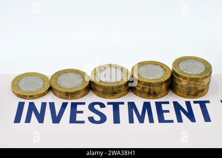 Britische ein-Pfund-Münzen in Säulen mit zunehmender Größe neben einem Investitionsdokument. Keine Personen. Stockfoto