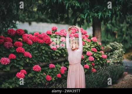 Ein kleines Ballerina-Mädchen, das im Hortensie-Garten tanzt, im Tutu-Kleid Stockfoto