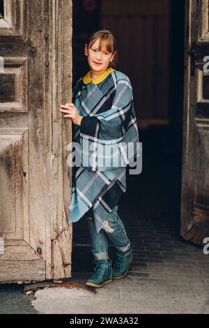 Modeporträt eines hübschen kleinen Mädchens mit blauem kariertem Poncho Stockfoto