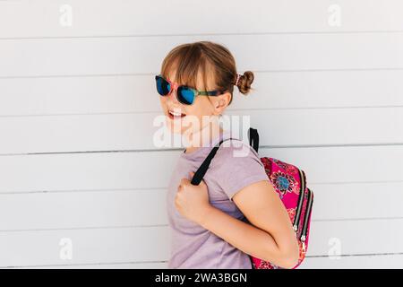 Porträt eines lustigen jungen Mädchens mit Sonnenbrille und Rucksack Stockfoto