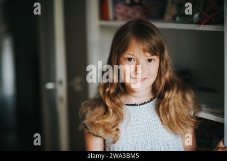 Innenporträt eines entzückenden Mädchens mit lockigen Haaren und Sommersprossen im Gesicht Stockfoto