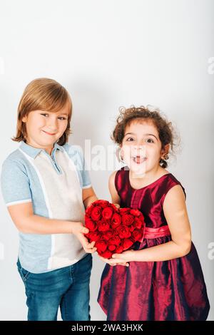 Studio-Aufnahme von zwei lustigen Kinderfreunden, die großes rotes Herz halten Stockfoto