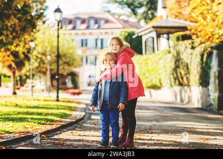 Große Schwester und kleiner Bruder spielen im Herbstpark, Kinder tragen warme Jacken Stockfoto