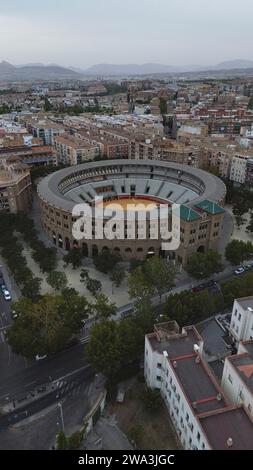 Drohnenaufnahmen der Plaza de Toros de Granada in Spanien, historischer Neo-Mudéjar-Stierkampfarena mit hufeisenförmigen Bögen und Ziegel Fassade sowie Panorama der Stadt Granada Stockfoto