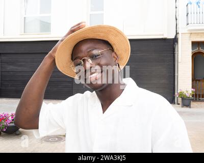 Porträt eines sorglosen jungen afroamerikanischen Mannes, der einen Hut trägt und während eines Urlaubs in die Kamera schaut Stockfoto