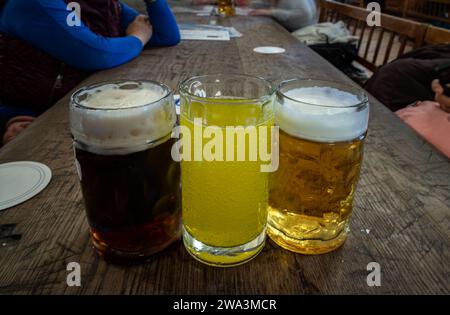 Drei Gläser verschiedener Sorten von kaltem, leckerem Bier stehen auf einem Holztisch in einem Restaurant hintereinander. Tisch für die Gesellschaft von Freunden, Platz für Text, Sele Stockfoto