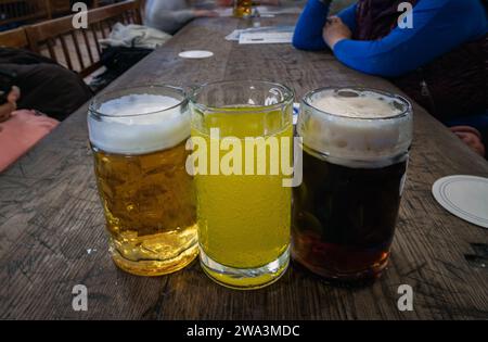 Drei Gläser verschiedener Sorten von kaltem, leckerem Bier stehen auf einem Holztisch in einem Restaurant hintereinander. Tisch für die Gesellschaft von Freunden, Platz für Text, Sele Stockfoto