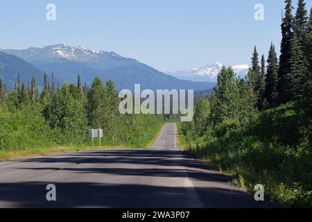 Enge, verkehrsfreie Straße führt in endlosen Steigungen durch zerklüftete Berglandschaften, Wälder und schneebedeckte Berge, Wildnis und Stewart Cassiar Hi Stockfoto