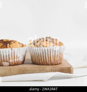 Vanillemandelmuffins auf einem Schneidebrett, hausgemachte Mandelmuffins im Bäckereistil auf weißem Hintergrund Stockfoto