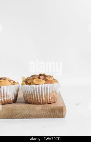 Vanillemandelmuffins auf einem Schneidebrett, hausgemachte Mandelmuffins im Bäckereistil auf weißem Hintergrund Stockfoto