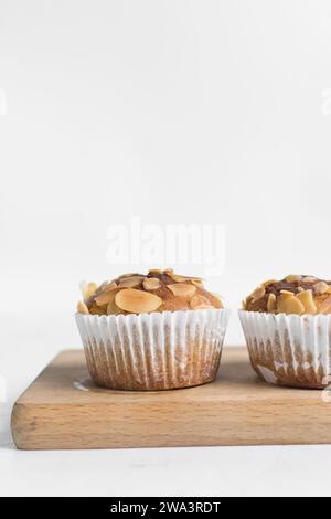 Vanillemandelmuffins auf einem Schneidebrett, hausgemachte Mandelmuffins im Bäckereistil auf weißem Hintergrund Stockfoto