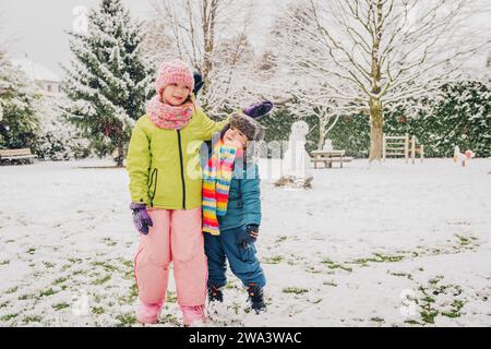 Zwei entzückende Kinder spielen zusammen im Snowpark und tragen warme Winterkleidung Stockfoto