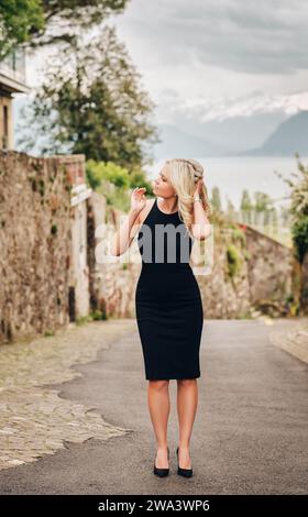 Außenporträt einer jungen blonden Frau in schwarzem Kleid Stockfoto