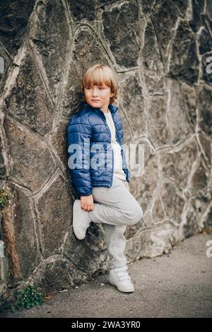 Outdoor-Modeporträt eines stilvollen Jungen mit blauer gepolsterter Jacke Stockfoto