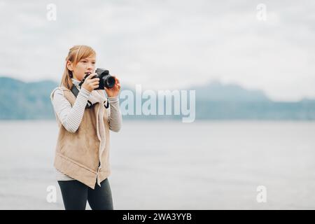 Niedliches kleines Mädchen, das einen schönen Tag am Genfer See genießt, Fotos mit einer dslr-Kamera macht und eine beige Jacke trägt. Reisen Sie mit Kindern. Bild aufgenommen i Stockfoto