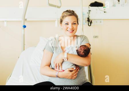 Glückliche junge Mutter mit neugeborenem Kind im Krankenhaus nach der Geburt Stockfoto