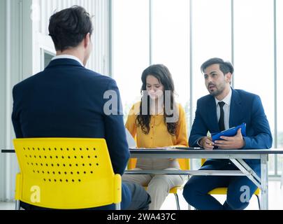 Das Konzept des Vorstellungsgesprächs. Vielfältiges HR-Team, das ein Vorstellungsgespräch mit einem Mann in einem Geschäftsbüro führt. Personalteam, das einen potenziellen Kandidaten interviewt. Stockfoto