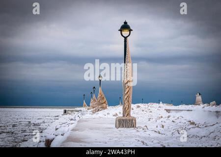 Lake Erie Pier in Ontario, Kanada, Lichtmasten mit Eis bedeckt. Natürliche Eisskulpturen, die aus Wellen während eines Wintersturms entstanden sind Stockfoto