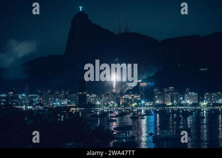 Blick aus der Perspektive auf das Feuerwerk in der Botafogo Bay in Rio de Janeiro, Brasilien bei Nacht mit der berühmten Christus-Erlöser-Statue auf Corcovado Stockfoto