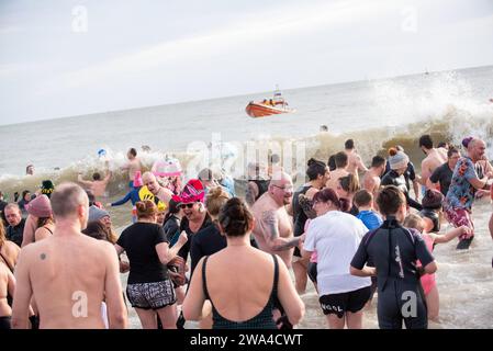 Ramsgate, Großbritannien. Januar 2024. Die Leute betreten das Wasser in Ramsgate für das Silvesterbad, während das Boot eines Schutzes aus der Ferne beobachtet. 300 Einheimische und Besucher versammelten sich am Main Sands von Ramsgate zum Neujahrsbad. Die Veranstaltung findet aus Wohltätigkeits- und lustigen Gründen statt. (Foto: Krisztian Elek/SOPA Images/SIPA USA) Credit: SIPA USA/Alamy Live News Stockfoto