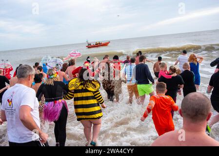 Ramsgate, Großbritannien. Januar 2024. Die Leute betreten das Wasser in Ramsgate für das Silvesterbad, während das Boot eines Schutzes aus der Ferne beobachtet. 300 Einheimische und Besucher versammelten sich am Main Sands von Ramsgate zum Neujahrsbad. Die Veranstaltung findet aus Wohltätigkeits- und lustigen Gründen statt. (Foto: Krisztian Elek/SOPA Images/SIPA USA) Credit: SIPA USA/Alamy Live News Stockfoto