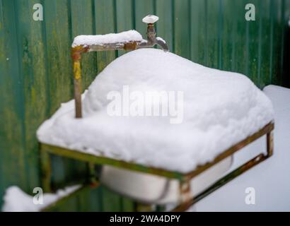 Waschbecken im Freien voller Schnee und gefrorenem Wasserhahn, keine Leute Stockfoto