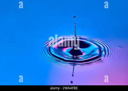 Ein Wassertropfen, der ins Wasser fällt und Wellen erzeugt Stockfoto