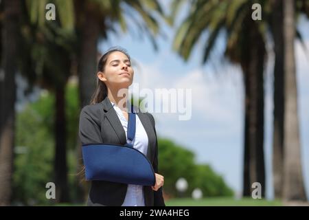 Rekonvaleszenz-Executive mit gebrochenem Arm, der frische Luft in einem Park atmet Stockfoto