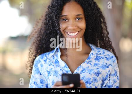 Vorderansicht Porträt einer glücklichen Frau, die Sie mit Smartphone ansieht Stockfoto