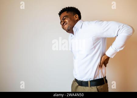 Porträt eines jungen Geschäftsmannes, der Schmerzen im Rücken hat. Kopieren Sie einen Platz auf dem Bild für Ihren Text oder Ihre Werbung. Stockfoto