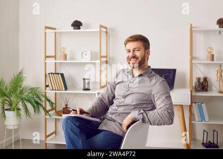 Porträt eines fröhlichen, stilvollen und selbstbewussten Mannes, der in Notizbuch schreibt Stockfoto