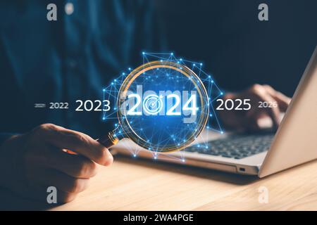 Wachstum des Unternehmens im Jahr 2024. Handlupe für Geschäftsleute mit Laptop. Neugründung und Zielvorgabe. Pläne und Vision für 2024 Jahre. Da Stockfoto