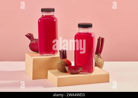 Mockup-Szene für Werbung für Fruchtsaftprodukte mit Flaschen ohne Marke auf Podesten mit Rote-Bete-Scheiben auf rosa Hintergrund. Rote-Bete-Saft könnten wir sein Stockfoto