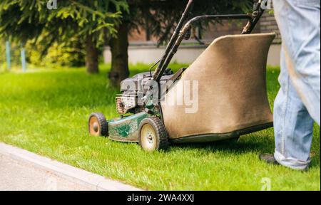 Der Arbeiter mäht den Rasen mit einem Rasenmäher. Rasenmähen im Garten. Stockfoto