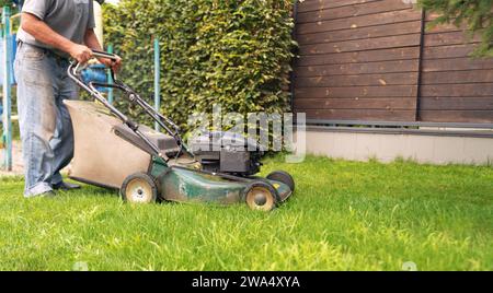 Der Gärtner mäht das Gras mit einem Rasenmäher auf dem Hof. Stockfoto