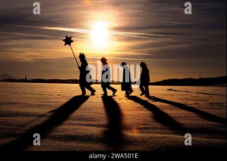 05.01.2022, Vorschau: Heilige Drei Könige. Sternsinger der katholischen Gemeinde hl. Familie Kaufbeuren. Vier Sternsinger laufen durch die verschneite Landschaft, im tiefstehenden Abendsonnen werfen sie lange Schatten. 05.01.2022, Sternsinger 05.01.2022, Sternsinger *** 05 01 2022, Preview Epiphany carol Sängerinnen aus der katholischen Pfarrei St. Familie Kaufbeuren vier carol-Sänger spazieren durch die verschneite Landschaft und werfen lange Schatten in der tiefen Abendsonne 05 01 2022, carol-Sänger 05 01, carol-Sänger 05 01 2022 Stockfoto