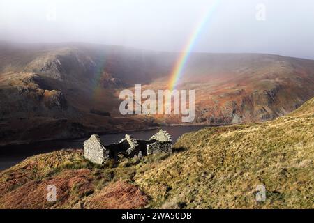 Regenbogenbogen über einem Ruinen Gebäude in der Nähe der Old Corpse Road mit Blick auf Haweswater, Lake District, Cumbria, Großbritannien, Stockfoto