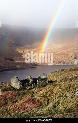 Regenbogenbogen über einem Ruinen Gebäude in der Nähe der Old Corpse Road mit Blick auf Haweswater, Lake District, Cumbria, Großbritannien, Stockfoto