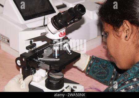 Die Pathologin wechselt die Linse der Beobachtungsmaschine. Indien Stockfoto