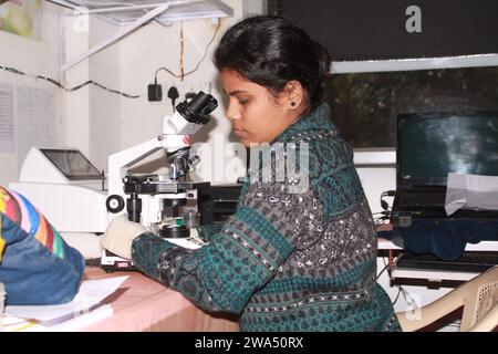 Pathologin mit Mikroskop untersuchen. Indien Stockfoto