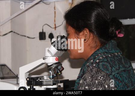 Pathologin mit Mikroskop untersuchen. Indien Stockfoto