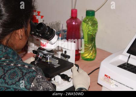 Pathologin mit Mikroskop untersuchen. Indien Stockfoto