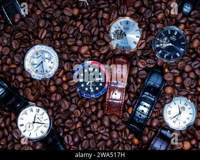 Kaffeezeit - sechs Armbanduhren und Kaffeebohnen auf einem Tisch Stockfoto