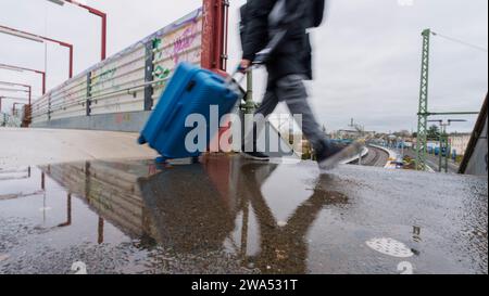 Bad Vilbel, Deutschland. Januar 2024. Ein Mann mit Koffer benutzt die provisorische Brücke am Bahnhof Bad Vilbel. Vom 2. Januar bis zum 18. Februar werden auf dieser Strecke keine Züge mehr verkehren, bevor der komplett sanierte Abschnitt zwischen Frankfurt West und Bad Vilbel endlich in Betrieb genommen wird. Es wurde ein Ersatz-Bus-Service eingerichtet. Die Bahnstrecke wurde seit 2017 von zwei auf vier Gleise erweitert, von denen zwei dann nur noch von S-Bahn-Zügen genutzt werden. Damit soll ein Engpass im Schienennetz beseitigt werden. Darlegung: Andreas Arnold/dpa/Alamy Live News Stockfoto