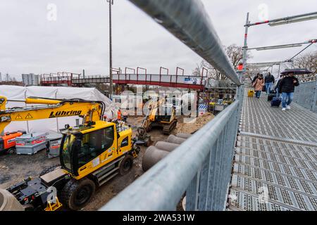 Bad Vilbel, Deutschland. Januar 2024. Eine Gruppe von Fahrgästen nutzt die provisorische Brücke am Bahnhof Bad Vilbel. Vom 2. Januar bis zum 18. Februar wird diese Strecke vor der endgültigen Inbetriebnahme des komplett sanierten Abschnitts zwischen Frankfurt West und Bad Vilbel nicht mehr verkehren. Es wurde ein Ersatz-Bus-Service eingerichtet. Die Bahnstrecke wurde seit 2017 von zwei auf vier Gleise erweitert, von denen zwei dann nur noch von S-Bahn-Zügen genutzt werden. Damit soll ein Engpass im Schienennetz beseitigt werden. Darlegung: Andreas Arnold/dpa/Alamy Live News Stockfoto