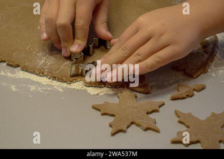 Kinderhände schneiden Kekse mit einem Ausstecher aus dem Teig Stockfoto