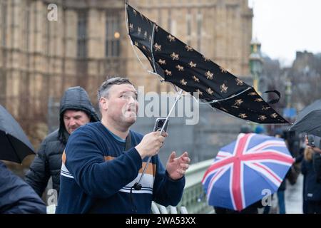 Bei starkem Regen auf der Westminster Bridge wird der Regenschirm von innen nach außen geblasen. Das Met Office hat eine gelbe Wetterwarnung für Storm Henk herausgegeben, der voraussichtlich Böen von bis zu 80 km/h in Teile Großbritanniens bringen wird. Bilddatum: Dienstag, 2. Januar 2024. Stockfoto