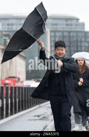 Bei starkem Regen auf der Westminster Bridge wird der Regenschirm von innen nach außen geblasen. Das Met Office hat eine gelbe Wetterwarnung für Storm Henk herausgegeben, der voraussichtlich Böen von bis zu 80 km/h in Teile Großbritanniens bringen wird. Bilddatum: Dienstag, 2. Januar 2024. Stockfoto